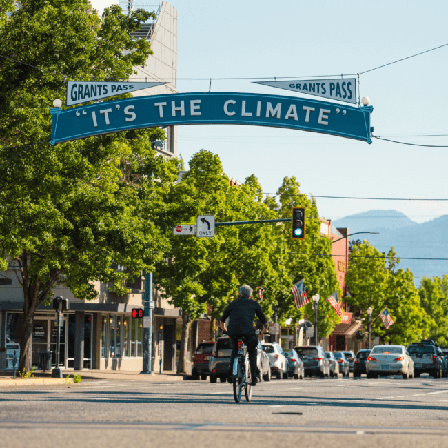 A person riding a bike down the street under a climate sign.